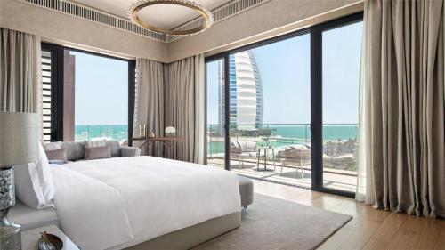 sypialnia z dużym białym łóżkiem i dużymi oknami w obiekcie Jumeirah Al Naseem Dubai w Dubaju