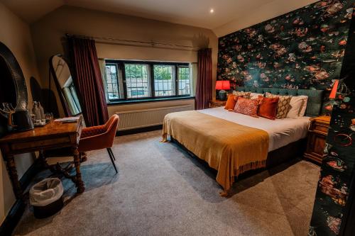 a bedroom with a bed and a desk and a window at The George in Hathersage