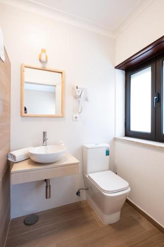 a bathroom with a toilet and a sink and a mirror at West Side Guesthouse in Peniche