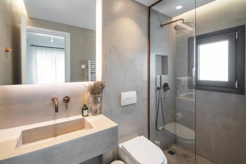 Un baño con lavabo, ducha e inodoro. en Maya Luxury Residence, en Aegenitissa