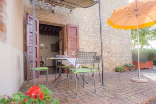 a patio with a table and chairs and an umbrella at Garden Relais Le Fontanelle in Montescudaio