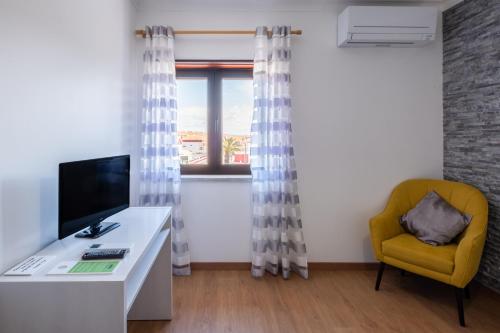 a room with a desk and a yellow chair and a window at West Side Guesthouse in Peniche