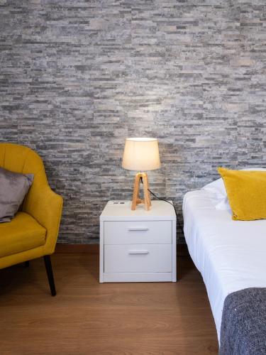 a bedroom with two beds and a lamp and a chair at West Side Guesthouse in Peniche