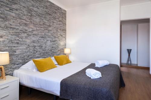 a bedroom with a bed and a brick wall at West Side Guesthouse in Peniche