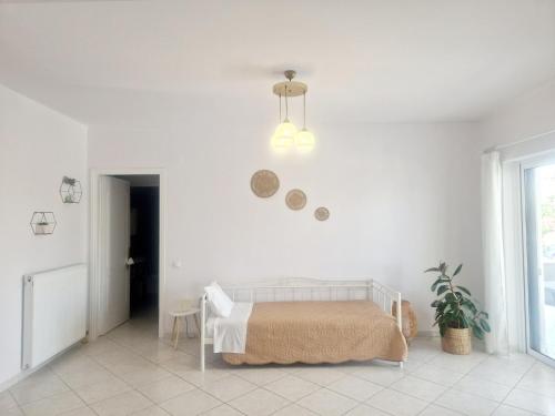 a white bedroom with a bed and a potted plant at Comfortable Apartment close to Rafina port in Rafina