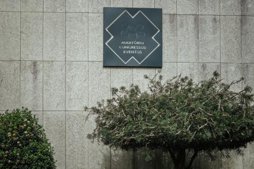a sign on the side of a building with a tree at Vilar Oporto Hotel in Porto
