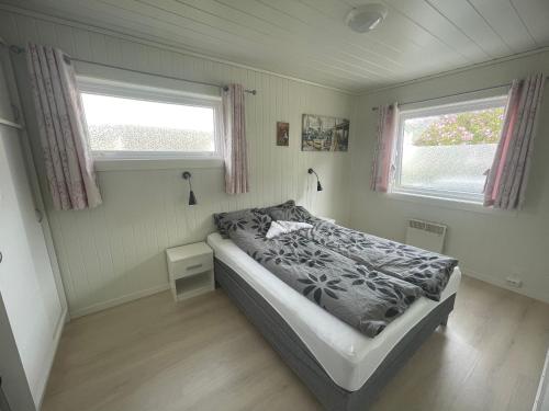 a small bedroom with a bed and two windows at Åndalsnes Luxury Stay - Full Apartment in Åndalsnes