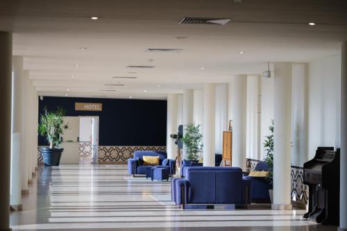 a lobby with blue chairs and a piano at Vilar Oporto Hotel in Porto