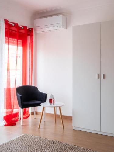 a black chair and a table in a room with a window at West Side Guesthouse in Peniche
