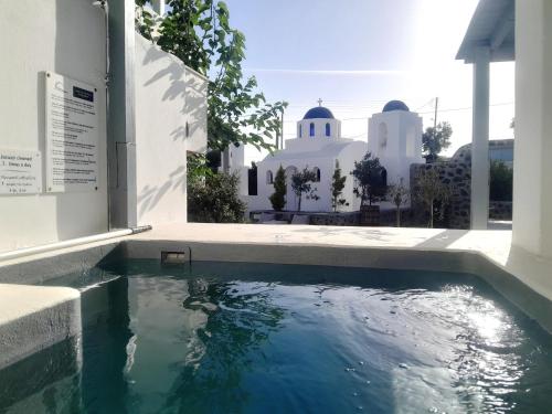 a swimming pool in front of a building with a mosque at Atlantis - by S paradise - outdoor jacuzzi & seaview in Oia