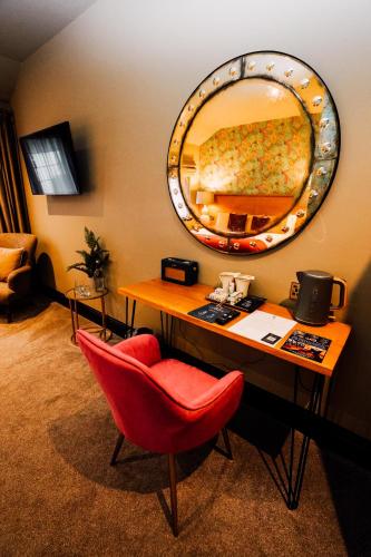 a desk with a red chair and a mirror at The George in Hathersage