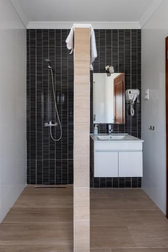 a bathroom with a shower and a sink and a mirror at West Side Guesthouse in Peniche