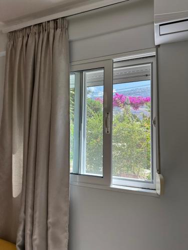 two windows with curtains in a room with flowers at Potami Seashell in Himare