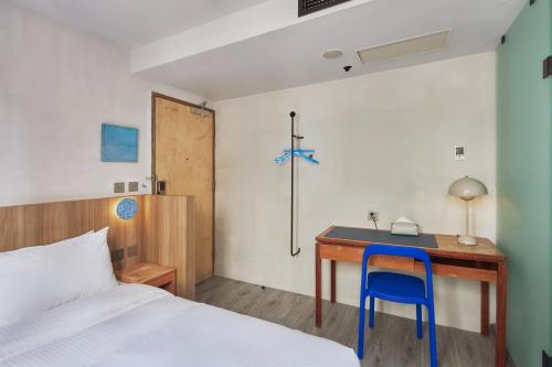 a bedroom with a desk with a bed and a blue chair at The Blue by Just Inn in Taipei