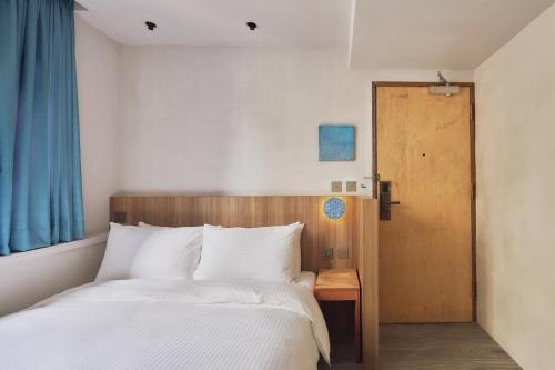 a bedroom with a white bed and a wooden door at The Blue by Just Inn in Taipei