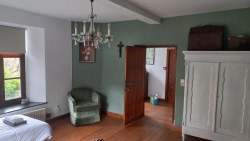 a bedroom with a bed and a chair and a chandelier at B&B Ferme1883 in Lierneux