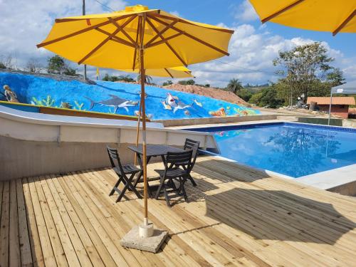 a table and chairs under an umbrella next to a swimming pool at Pousada Kart Clube in São João del Rei