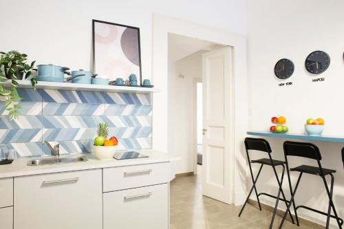 a kitchen with white cabinets and black stools at Bausan Avenue in Naples