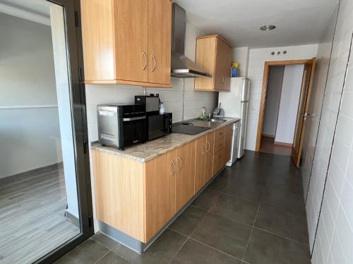 a kitchen with wooden cabinets and a microwave at Ánade Real Guest House in Daimiel