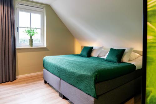 a bedroom with a bed with green sheets and a window at Othmar Herberg in Ootmarsum