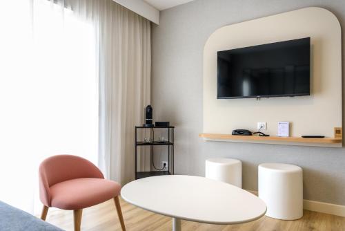 a living room with a white table and a tv at Best Western Plus Ajaccio Amirauté in Ajaccio