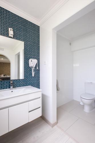 a bathroom with a white sink and a toilet at West Side Guesthouse in Peniche
