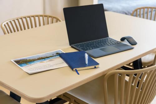 a laptop computer on a table with a notebook and a mouse at Best Western Plus Ajaccio Amirauté in Ajaccio