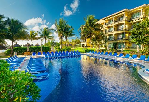 un complejo con una piscina con sillas y un edificio en Hotel Marina El Cid Spa & Beach Resort - All Inclusive, en Puerto Morelos