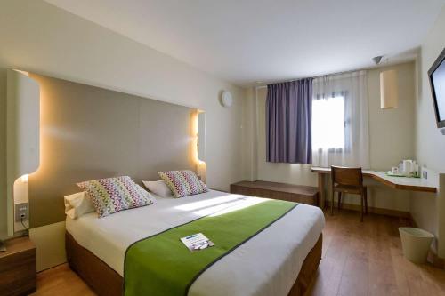 Cette chambre comprend un grand lit et un bureau. dans l'établissement Travelodge Málaga Airport, à Malaga