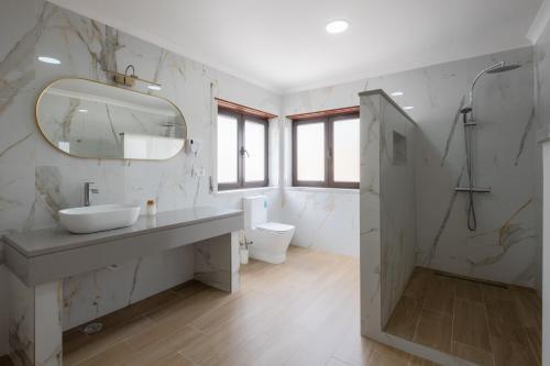 a white bathroom with a sink and a mirror at West Side Guesthouse in Peniche