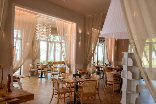 a restaurant with tables and chairs and windows at Hotel Anna Villa in Balatonföldvár