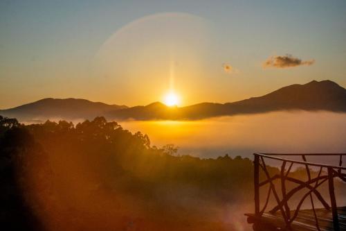 a misty sunrise with the sun rising over the mountains at Recanto das Estrelas in Aiuruoca