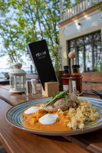 a plate of food with eggs and meat on a table at Hotel Anna Villa in Balatonföldvár