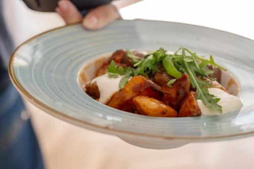 a person holding a bowl of food on a plate at Hotel Anna Villa in Balatonföldvár