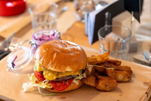 a sandwich and french fries on a wooden plate at Hotel Anna Villa in Balatonföldvár