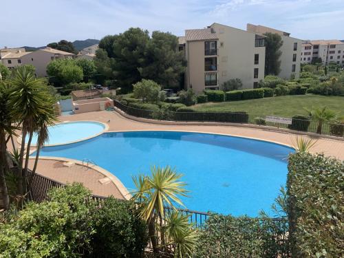 una grande piscina blu con alberi e edifici di Appartement Domaine de la Coudouliere + piscine (mai à octobre) a Six-Fours-les-Plages
