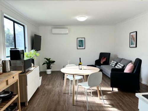 a living room with a table and a couch at Bowerbird Cottage in Camberwarra