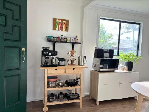 a kitchen with a table with a microwave and a coffee maker at Bowerbird Cottage in Camberwarra