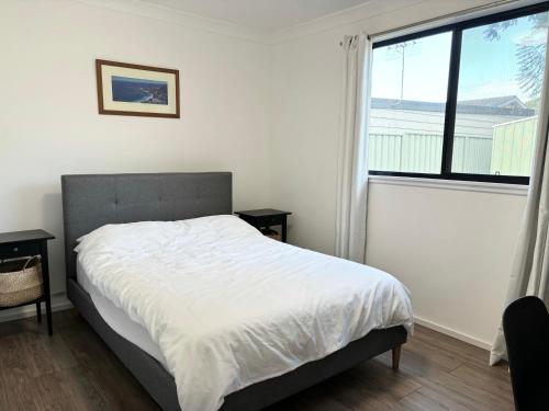 Un dormitorio con una cama y una ventana grande. en Bowerbird Cottage, en Camberwarra