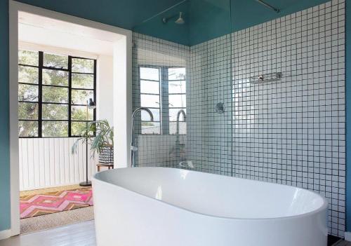 Una bañera en un baño con azulejos azules. en Southern Sky House, en Paarl