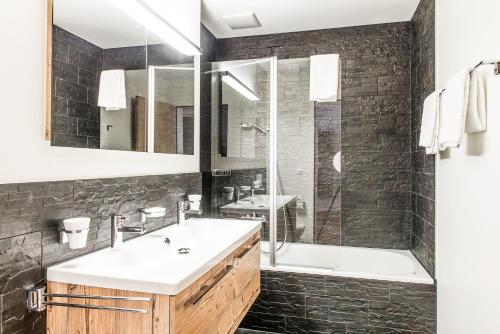 a bathroom with a sink and a tub and a mirror at Titlis Resort in Engelberg