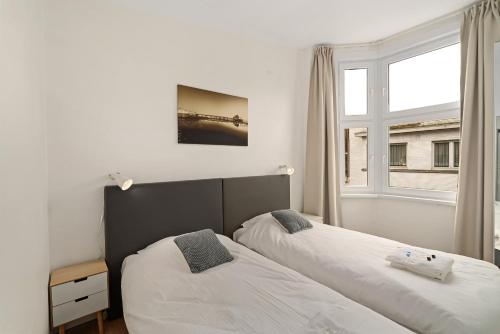 1 dormitorio con 2 camas junto a una ventana en Kolonel - Charmant & lichtrijk app aan zee 4p en Blankenberge
