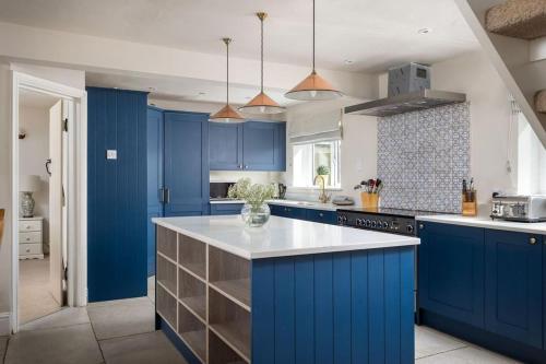 a kitchen with blue cabinets and a white counter top at Stanway House, 8 bedroom, 8 Bath in Cheltenham