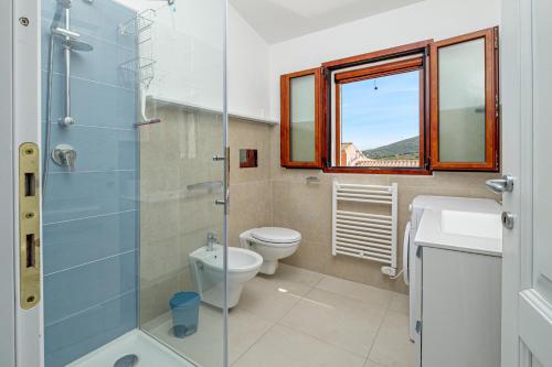 a bathroom with a toilet and a glass shower at Villa Poldina in Budoni