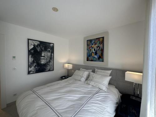 une chambre avec un lit blanc avec deux tableaux au mur dans l'établissement Appartement centre ville 7 Lecerf, à Cannes