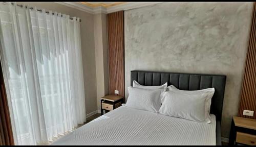 a bedroom with a white bed with white pillows at Hotel DEMOLI in Pogradec