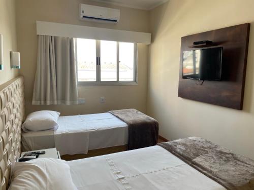 a hotel room with two beds and a flat screen tv at Hotel Marbor in Mogi das Cruzes