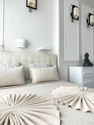 a white bedroom with a large bed with a large headboard at Trigon Palace in Budapest
