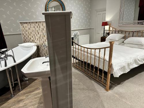 ein Schlafzimmer mit einem Kinderbett, einem Waschbecken und einem Bett in der Unterkunft Crown Hotel in Stamford