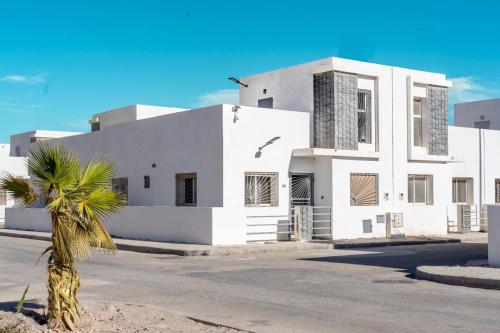 ダフラにあるDakhla Golden Sandsのヤシの木が前に立つ白い建物